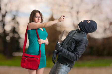 年轻女子捍卫与胡椒喷雾反对武装小偷用刀照片