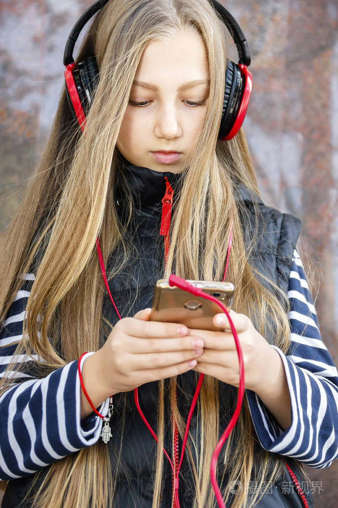美丽的城市女孩戴着耳机听音乐炭
