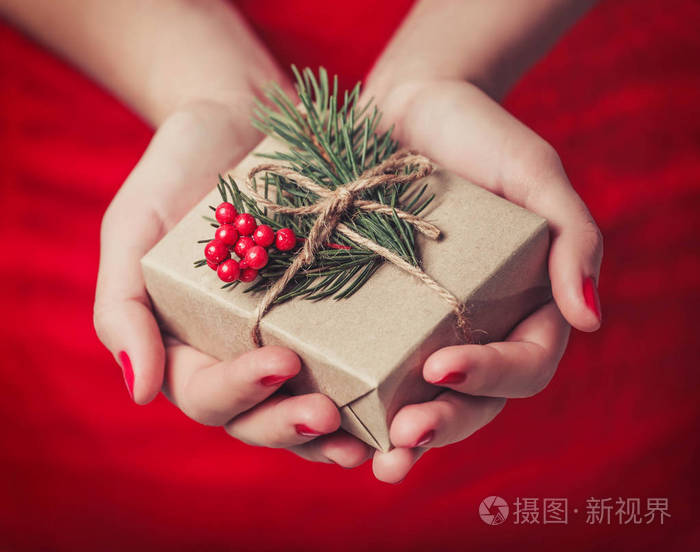 女性的双手托着杉树的树枝上闪亮的圣诞背景圣诞礼品盒节日礼物和装饰