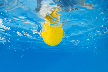 下降的柠檬片在蓝色的水溅的柠檬照片