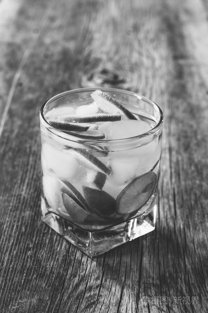 鸡尾酒玛格丽塔与柠檬和冰多维数据集在一张旧木桌特写,黑白照片