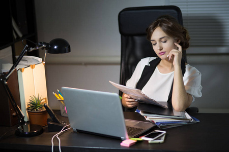 坐在她办公室里的工作场所的女商人照片