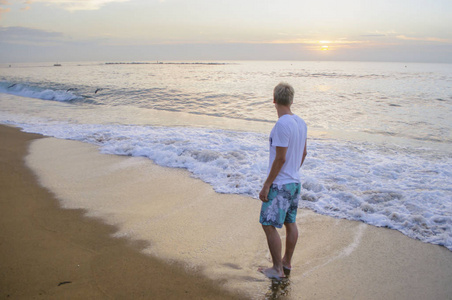 穿着短裤看着站在岸边的大海的年轻人照片