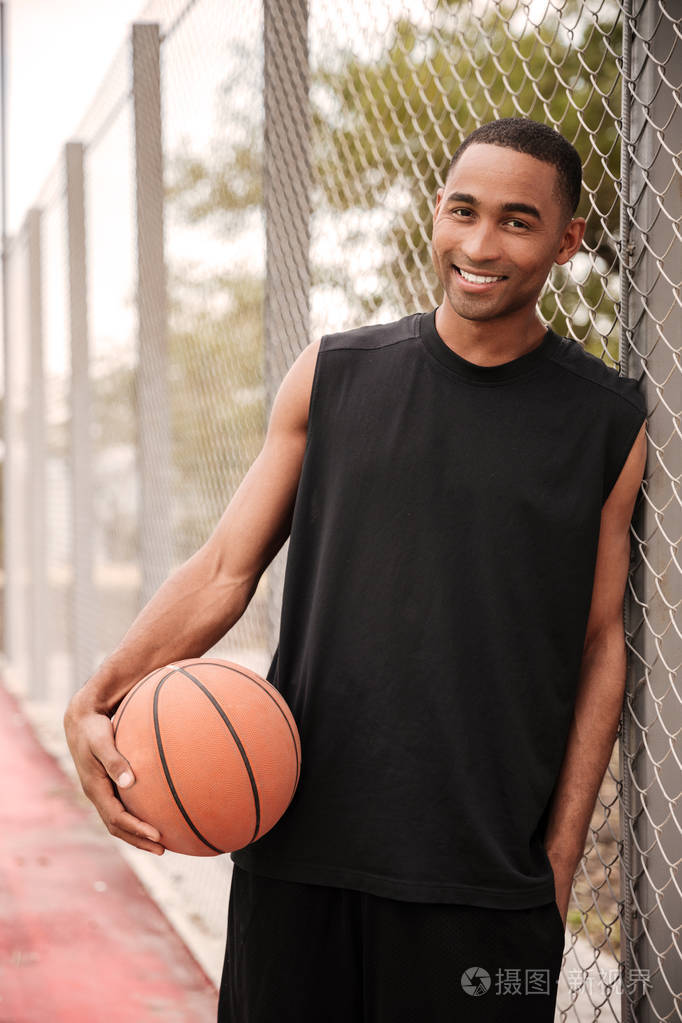 微笑着看着站在公园里的非洲篮球运动员