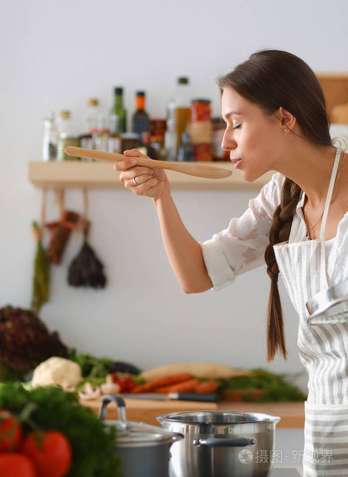 烹饪的女人在厨房里用木勺
