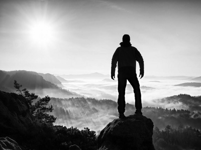 人剪影高爬上悬崖.爬到山顶的徒步旅行者欣赏的景色照片