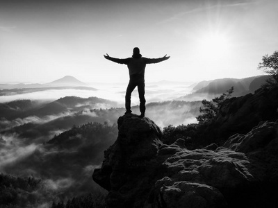 人剪影高爬上悬崖.爬到山顶的徒步旅行者欣赏的景色照片