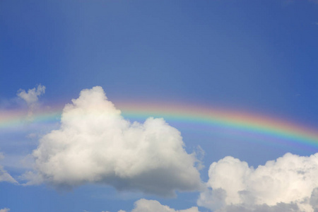 彩虹在蓝色的天空和洁白的云朵照片