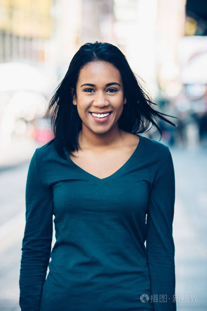 美丽年轻的拉丁女孩在城市的街道上行走和微笑