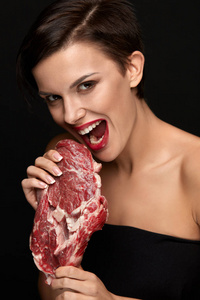 吃肉.美丽的女人咬生红牛肉牛排肉照片