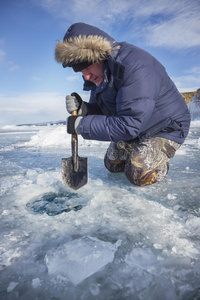 一个拿着铲子的人把湖里的冰裂开了照片