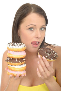 迷人的自然快乐的年轻女人拿着一堆冰甜甜圈