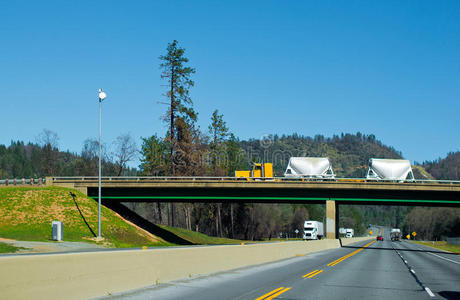 经典的黄色半卡车散装拖车在桥上横跨州际公路I5俄勒冈州