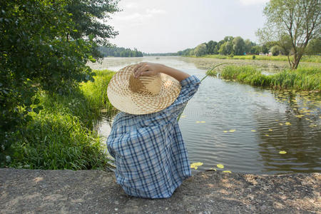 钓鱼的男孩用鱼竿拿着一只手草帽