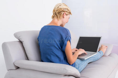 金发女人在沙发上用笔记本电脑