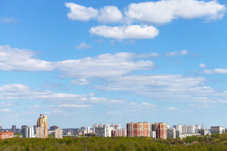 蓝色的春天天空笼罩着城市和绿色的树林