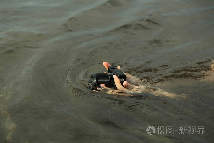 黑色湿的相机与镜头在拍摄海底的手中