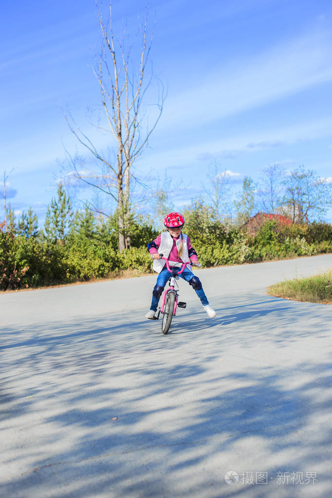 可爱的小女孩在公园里骑着自行车在一个阳光明媚的夏日的防御童年的