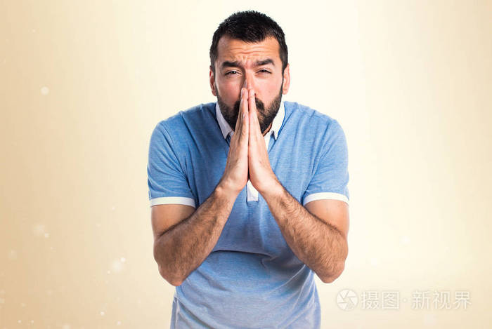 恳求赭石背景上的蓝色衬衫的男人