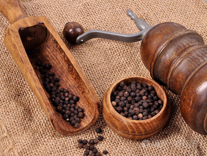 用木制背景上锅铲磨胡椒