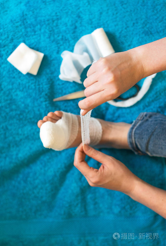 包扎她受伤的腿在家里的沙发上的女人