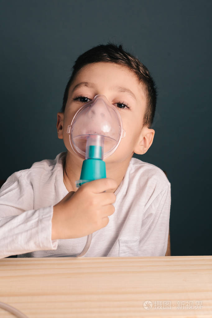一个可爱的小孩,与呼吸问题或哮喘的形象.烟雾从氧气面罩雾化器的视图