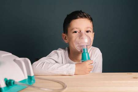 烟雾从氧气面罩雾化器的视图美丽生病的男孩吸入疗法由吸入的掩码