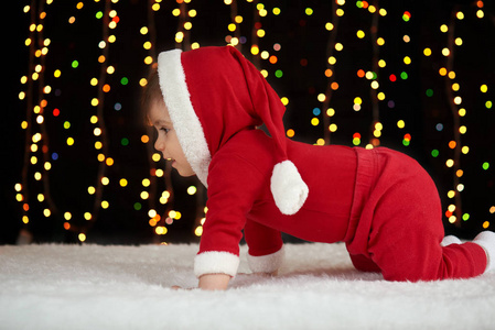 打扮成圣诞老人,博克灯在黑暗的背景下,冬天假日概念婴儿爬行照片