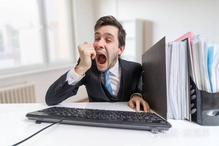 困了累了年轻人打哈欠在办公室里工作