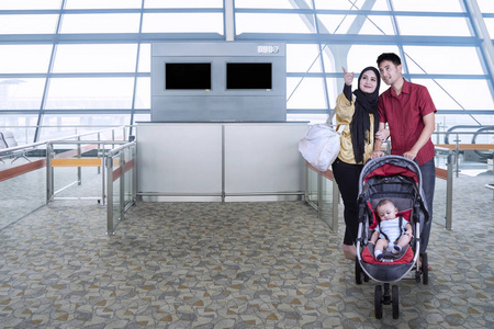 穆斯林家庭与机场推车婴儿车独轮手推车载重的和泥土偶像绿色的指已