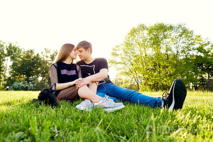 一对情侣拥抱坐在公园的草地上