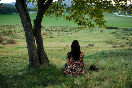 坐在树下,看在视图上的女人年轻的金发女人欣赏瑞士日内瓦湖的风景.