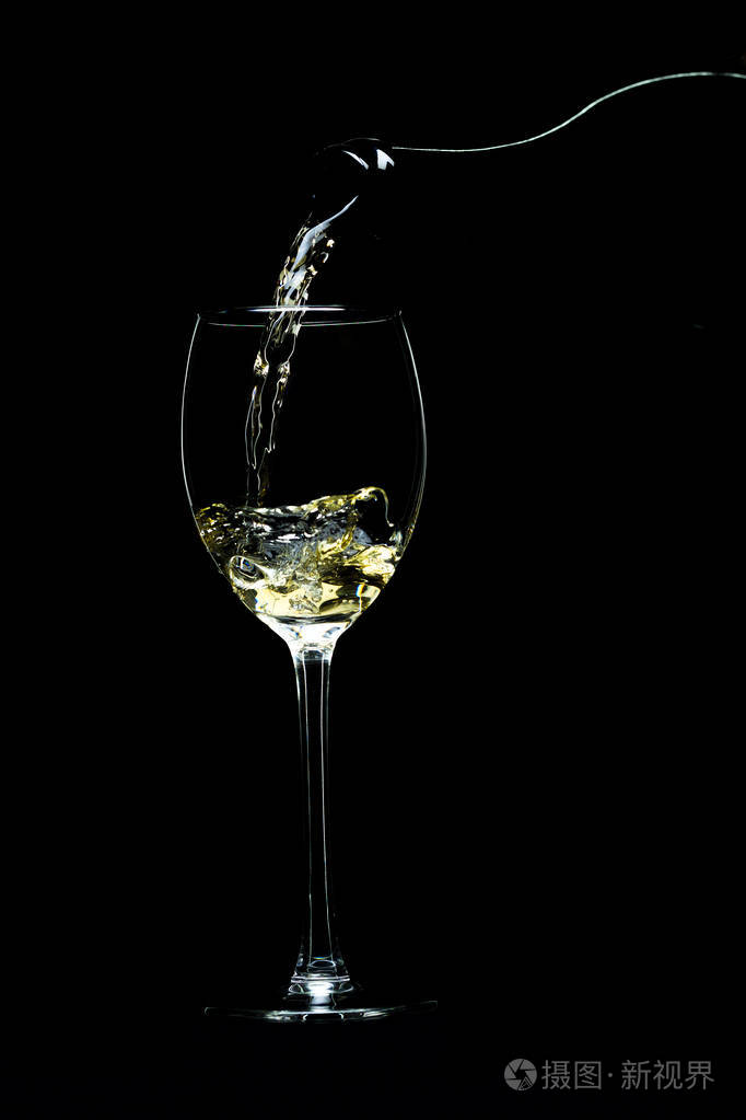 涌入黑色背景上的一杯酒