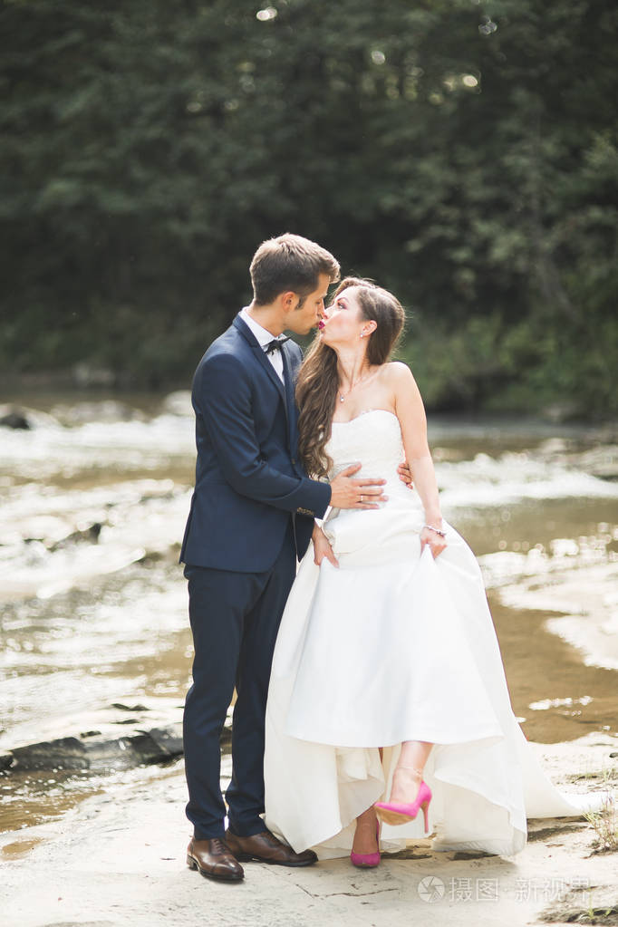 美丽婚礼情侣接吻和拥抱接近岸边的石头山区河流