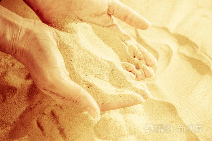 女性手释放掉沙的特写沙子流经手