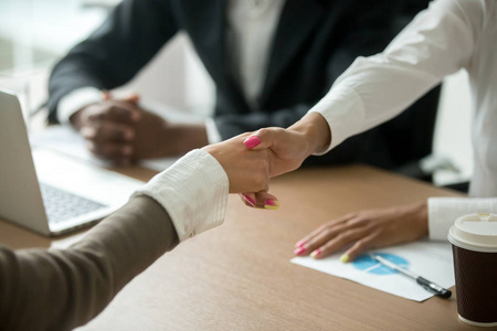 黑白女性在集体会议上握手,不同的女商人握手问候或做好事,表达尊重和