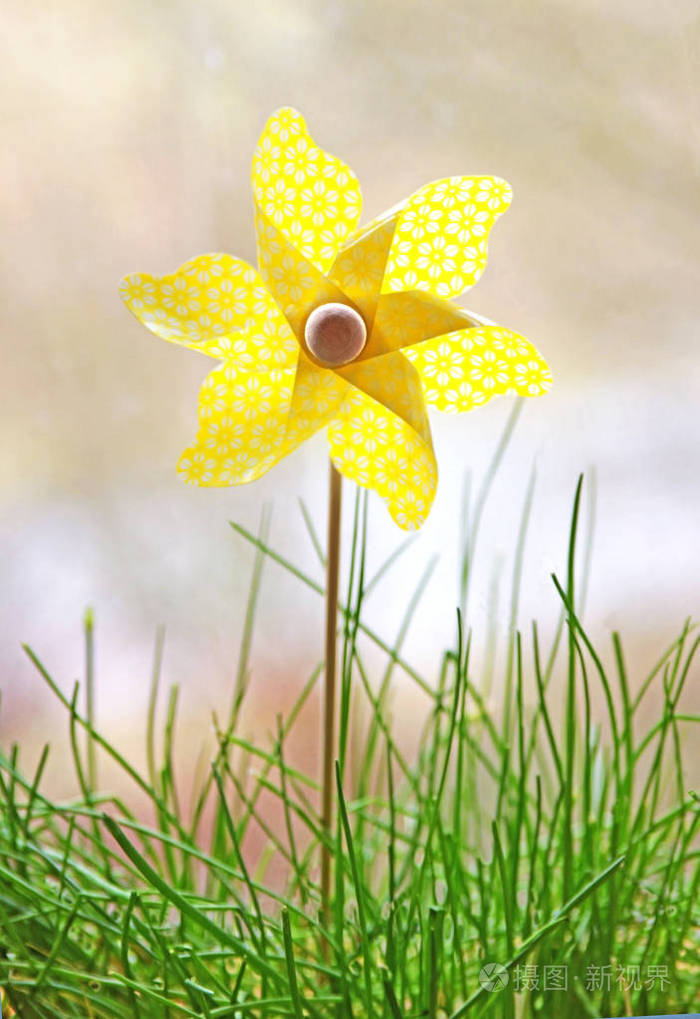 黄色风车玩具站在草地上