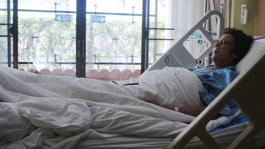 生病的女人在老年躺在病床上的氧气面罩下滴照片