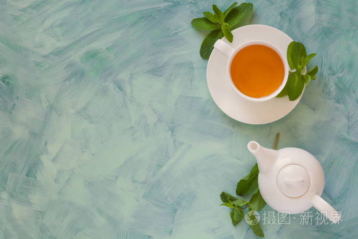 茶壶和杯子与绿色草药茶装饰薄荷叶木背景. 上面的风景. 复制空间.