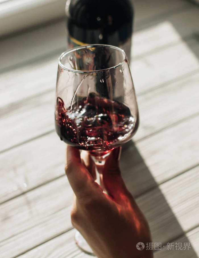 女人手拿酒杯桌上放着红酒