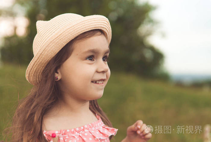 戴着草帽，留着长发的漂亮小女孩，夕阳下，在夏日的田野里远眺