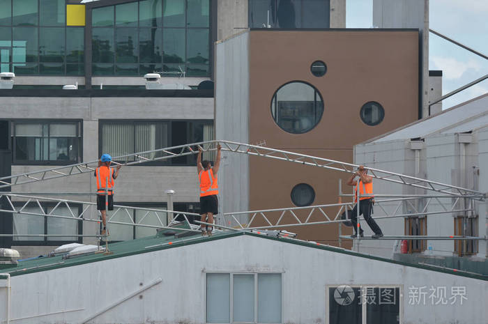 无法辨认的建筑工人在建筑物屋顶上组装金属框架。