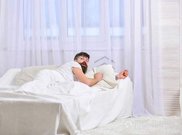 男人穿着衬衣躺在床上醒着背景上白窗帘起床和睡过头的概念一个惊讶的