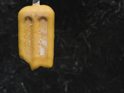 倒放黄色冰冻冰棍冰在夏天和黑暗的背景下倒放融化照片