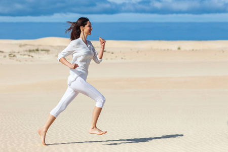 穿着运动服在沙漠里跑步的漂亮女孩.