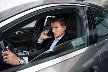 侧面视图的年轻英俊的商人看左边的肖像, 而驾驶汽车和通话照片