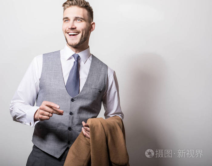 优雅的年轻英俊的男人手里拿着长而时尚的外套.