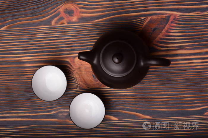 木制背景上有空杯的茶壶的俯视图