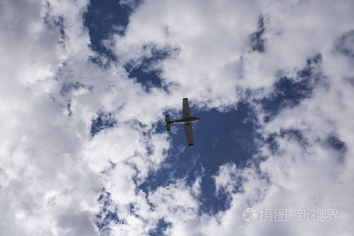 从地面上看到的在云层之间飞行的小飞机