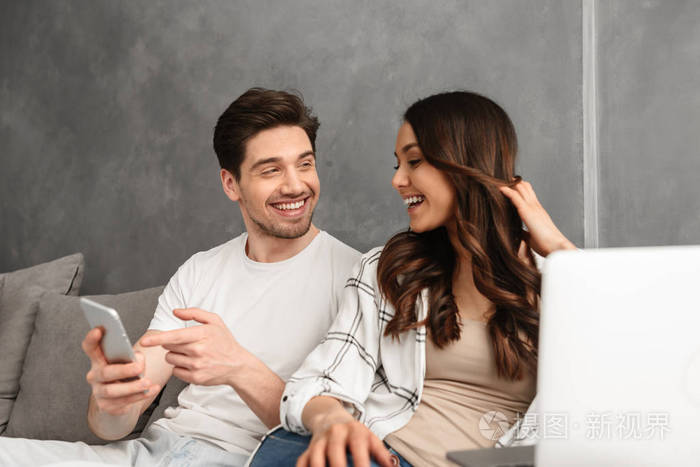 可爱的夫妻30岁的男人和女人在家里的客厅里休息微笑着使用笔记本电脑